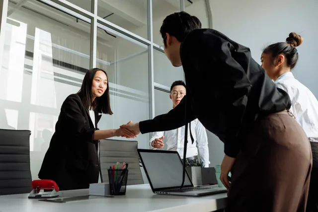 Group of business colleagues shaking hands during an office meeting. Lohnverhandlungen in der Schweiz: Vorbereitung, Argumente und Schritte